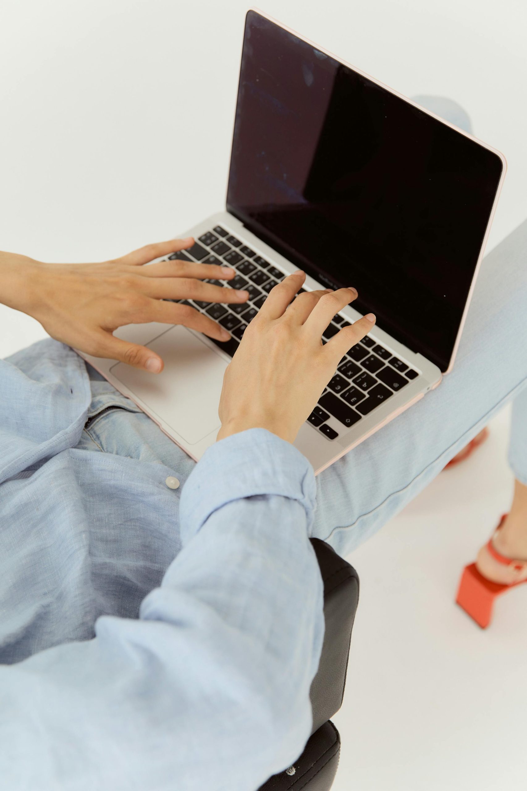 Overhead shot of a woman online shopping on a laptop with a white background.